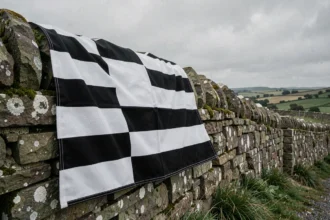 Drapeau breton Gwenn-ha-Du drapé sur un mur en granit breton avec bandes noires et blanches visibles